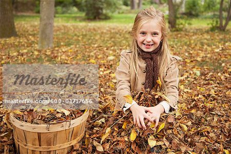 Portrait de jeune fille assise dans les feuilles de l'automne