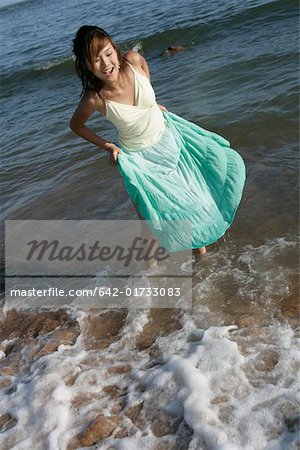 Young woman walking out of ocean, smiling, elevated view