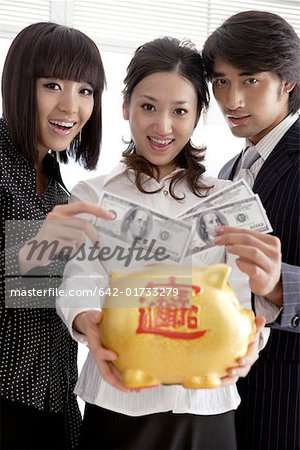 Portrait of young people holding piggy bank and paper currencies