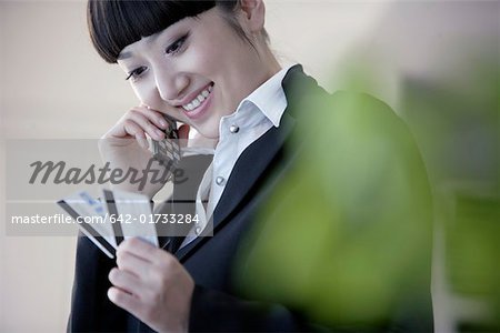 Gros plan d'une jeune femme à l'aide de téléphone portable et en regardant les cartes de crédit