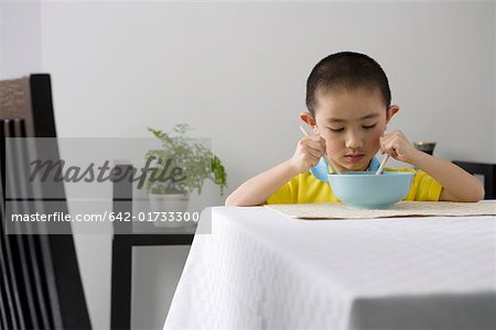 Garçon manger avec des baguettes