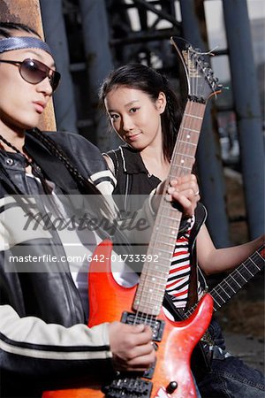 Young man and woman playing guitar, portrait