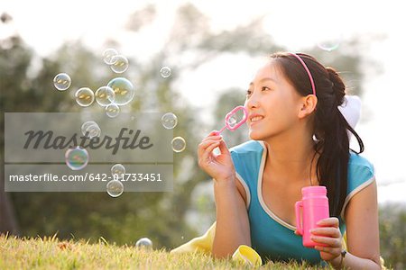 Young woman blowing bubbles, smiling
