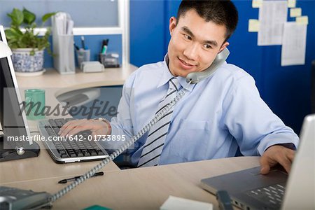Homme d'affaires au bureau avec téléphone et ordinateur portable