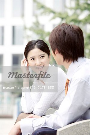 Businesswoman and businessman sitting on bench, smiling