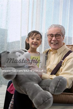 Petite fille et grand-père tenant des ours en peluche, sourire, portrait