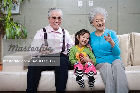 Mädchen sitzen mit Großvater und Großmutter, Lächeln