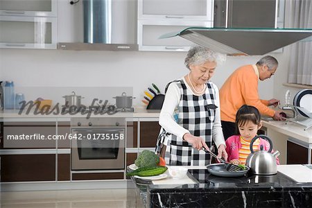Senior couple and granddaughter cooking in kitchen