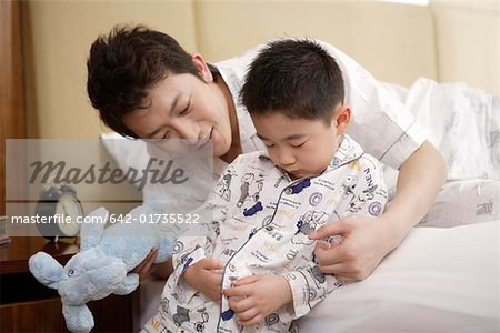 Vater und Sohn spielen mit der Puppe im Bett