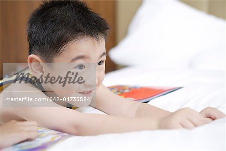 Gros plan d'un petit garçon couché sur le lit et souriant