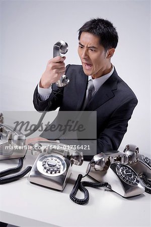 Businessman shouting in front of a telephone receiver