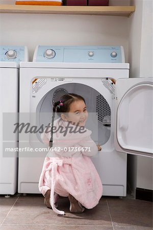 Portrait d'une jeune fille accroupie par machine à laver