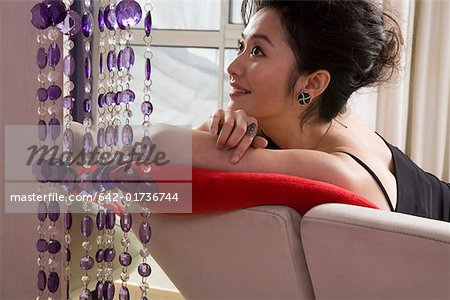 Jeune femme accoudée à une chaise et souriant