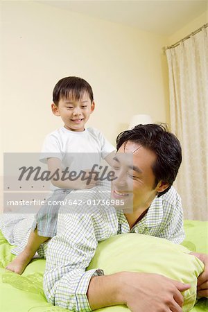 Son riding on father on bed