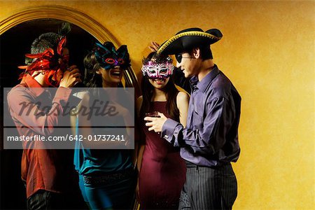 Jeune homme et jeune femme bavarder et boire au bal costumé