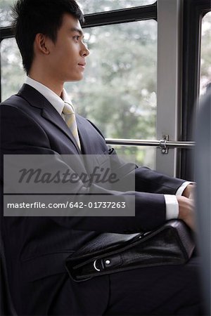 Businessman holding briefcase and sitting in bus