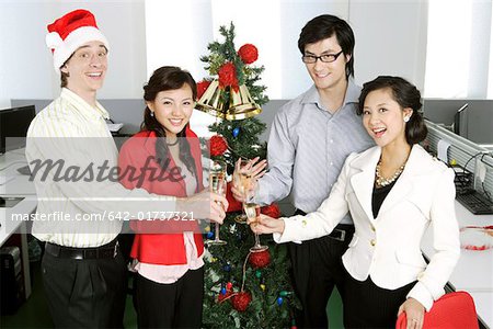 Toasting young men and young women in front of Christmas tree
