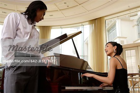 Junger Mann mit einer jungen Frau, die Klavier spielen