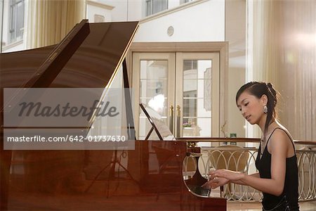 Young woman playing piano in hall