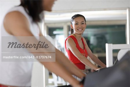Young men and young women standing on treadmill in gym