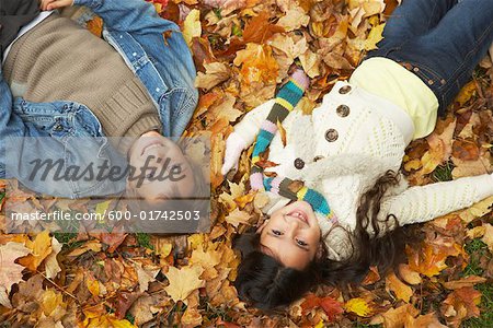 Kinder, die im Herbst Laub liegend