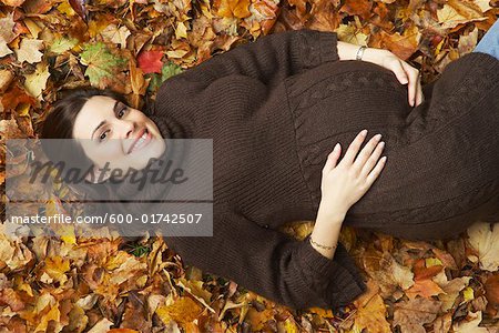 Femme enceinte se trouvant dans les feuilles d'automne