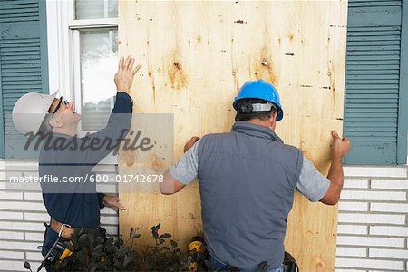 Travailleurs de la construction qui couvre la fenêtre avec le Conseil d'administration