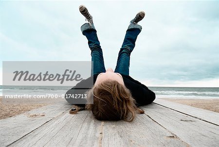 Fille regardant vers le haut dans le ciel sur la plage, Pays-Bas