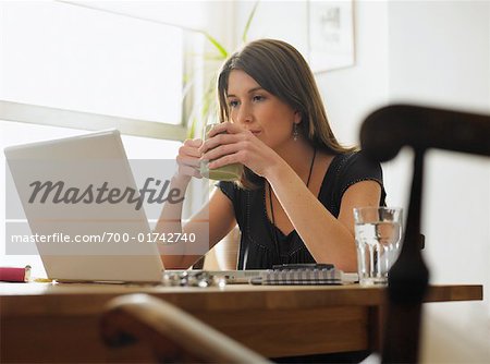 Portrait de femme assise au comptoir à l'aide d'ordinateur portable