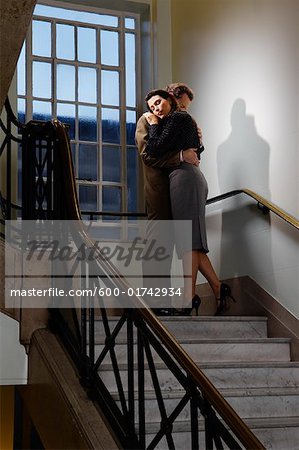 Businessman and Woman Hugging in Stairwell