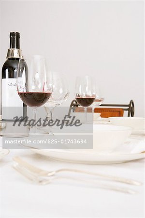 Weinflaschen und Weingläser mit Geschirr auf einem Esstisch