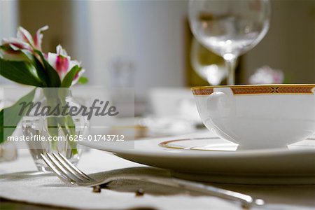 Close-up of a flower vase and a soup bowl on a dining table