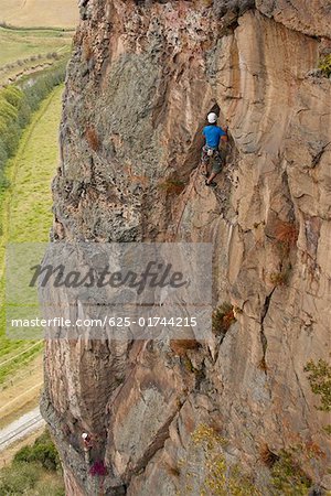 Ansicht von hinten von einem männlichen Felsenkletterer aufsteigend von einen steilen Felsen