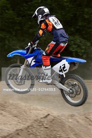 Side profile of a motocross rider performing jump on a motorcycle