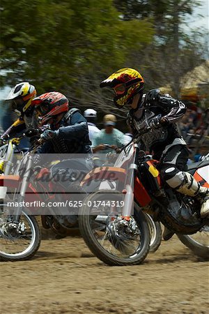 Side profile of three motocross riders riding motorcycles