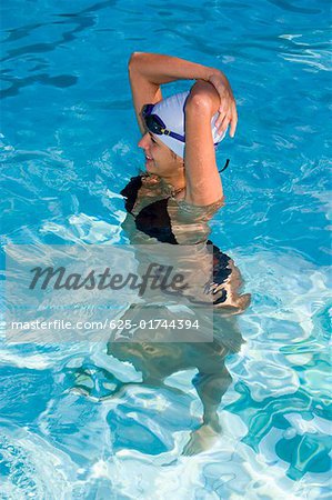 High angle view of a young woman standing in a swimming pool and smiling