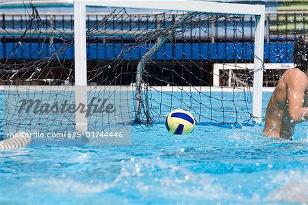 Water polo player in front of a goal post in a swimming pool