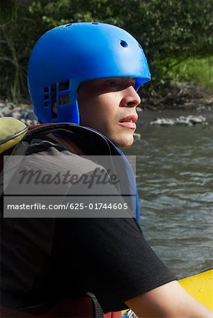 Side profile of a young man rafting in a river