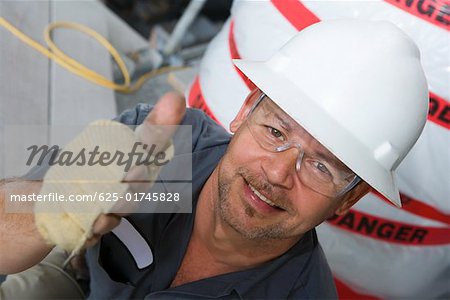 Portrait of a male construction worker showing a thumbs up sign and smiling