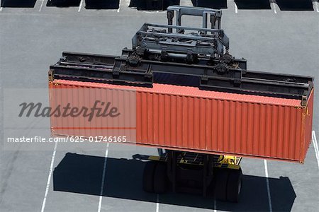 High angle view of a forklift picking up a cargo container at a commercial dock