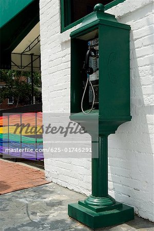Pay phone near a building with the rainbow flag in the background