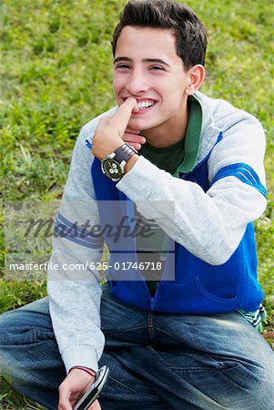 Gros plan d'un adolescent souriant avec son doigt sur sa bouche