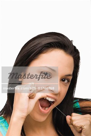 Portrait of a young woman flossing her teeth