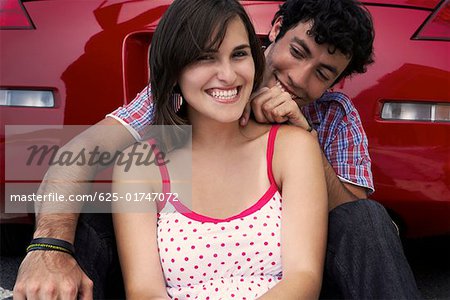 Close-up of a young couple sitting in front of a car