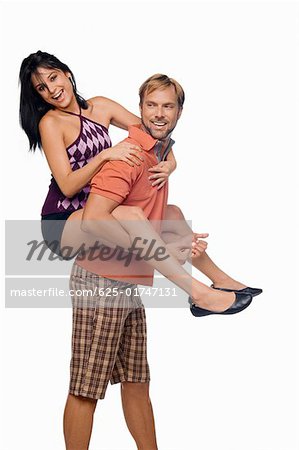 Portrait of a young woman riding piggyback on a mid adult man