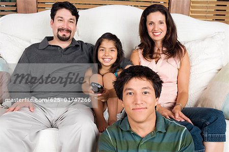 Portrait of a mid adult couple watching television with their son and daughter