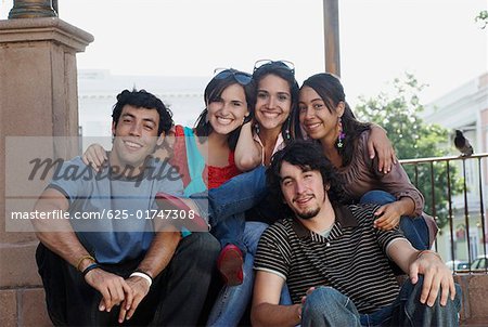 Portrait of three young women smiling with two young men