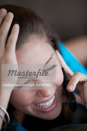 Gros plan d'une jeune femme parlant sur un téléphone mobile et souriant