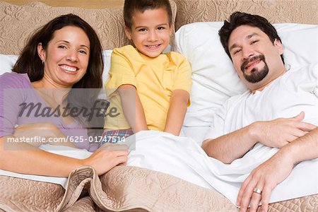 Portrait of a mid adult couple with their son on the bed