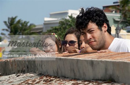 Profil de côté d'un jeune homme avec trois jeunes femmes donnant sur un mur de château, château de Morro, vieux San Juan, San Juan, Puerto Rico
